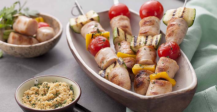 prato branco com quatro espetos de frango, abobrinha, tomate e pimentão