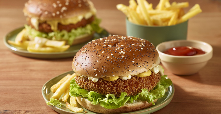 Dois pratos verde claros com batata frita e hambúrguer, um pote verde com batata frita e um pires com ketchup