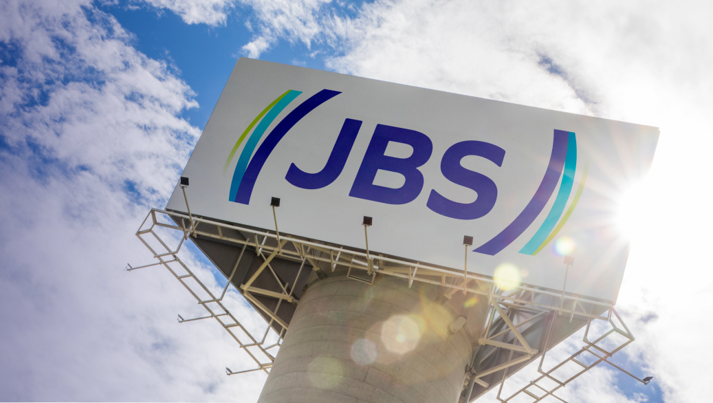 Placa da JBS em torre contra o céu azul