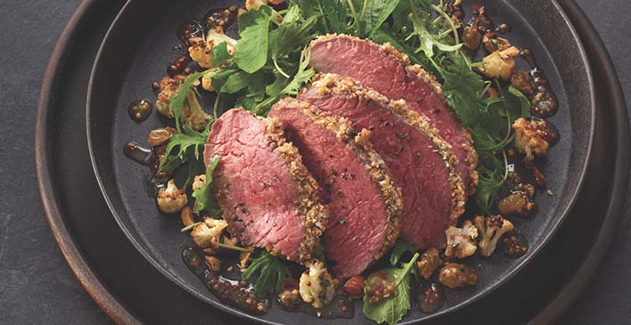 Prato preto com diversos temperos e um bife fatiado