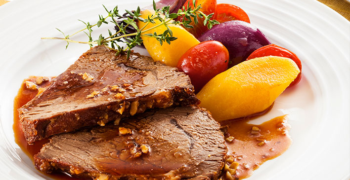 prato branco com tomates, batatas, cebola roxa tomilho e dois pedaços de bife com alho