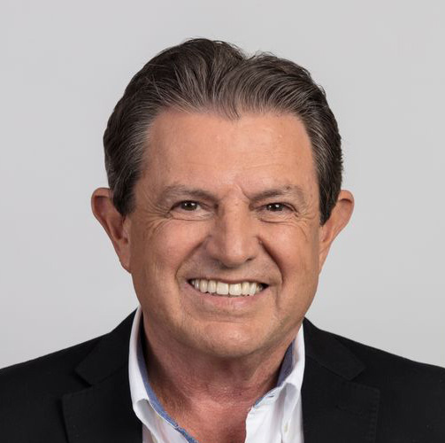 Nelson Dalcanale usando terno preto e camisa branca enquanto sorri