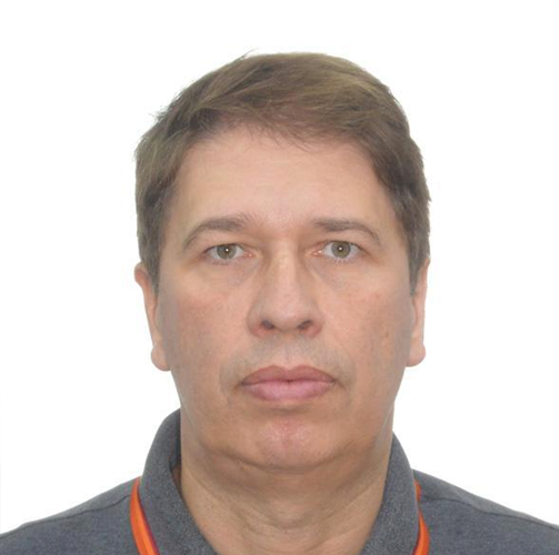 Helio Rubens usando uma camisa polo cinza enquanto olha para a câmera