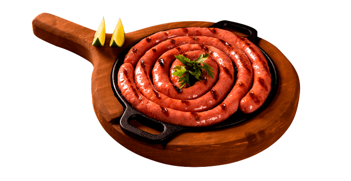 tábua de madeira com dois pedaços de limão e uma frigideira com linguiça e cheiro verde no centro