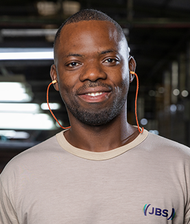 Man smiling in a beige t-shirt and orange earmuffs.