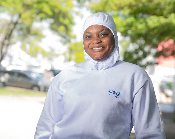 JBS employee smiling in white uniform and balaclava hood.