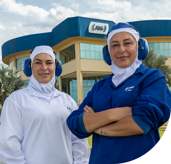 Two JBS employees smiling in front of the industrial facility.