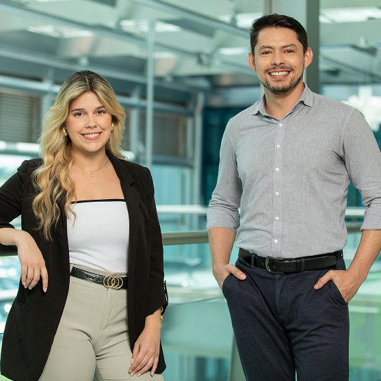 Smiling man and woman posing in a modern office.
