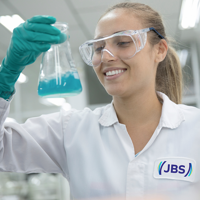 Two JBS employees smiling in front of the industrial facility.