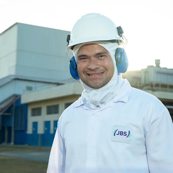 JBS employee in helmet and earmuffs smiles at the facility.