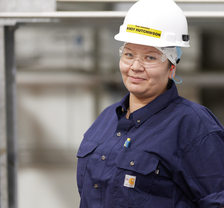 Female worker wearing hard hat and safety glasses at plant
