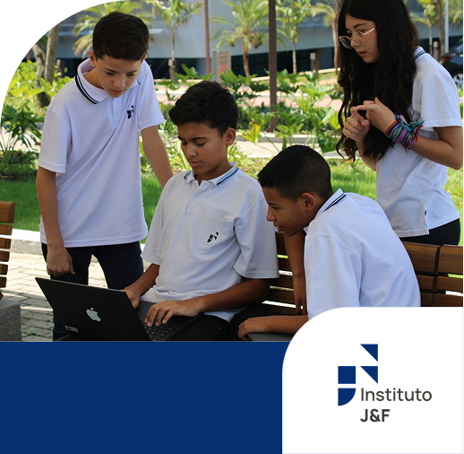 Jovens de uniforme usando laptop no jardim.