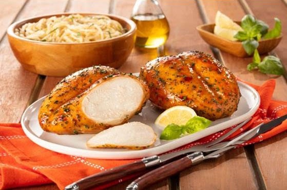 dois peitos de frango preparados sobre tigela oval decorada com fatia de limão e folhas