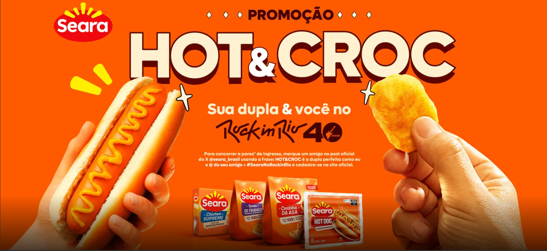 Imagem traz fundo laranja e traz uma mão segurando um hotdog com mostarda e uma outra mão segurando um empadinho de frango com os dedos, nessa mesma imagem tem quatro embagens de produtos Chicken Supreme, Iscas de frango, Coxinha da asa e salsicha hotdog, e também tem uma chamada: “Promoção Hot e croc Sua dupla e você no Rock in Rio 40”, também traz o regulamento da campanha.